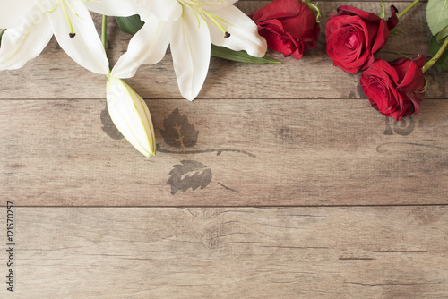 Fototapeta Naklejka Na Ścianę i Meble -  Floral frame with stunning white lilies and red roses on wooden background. Copy space. Wedding, gift card, valentine's day or mother's day background