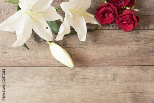 Fototapeta Naklejka Na Ścianę i Meble -  Floral frame with stunning white lilies and red roses on wooden background. Copy space. Wedding, gift card, valentine's day or mother's day background