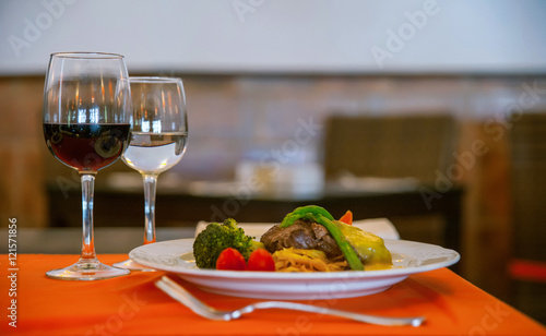 Elegant restaurant setup table with wine, water and main course 