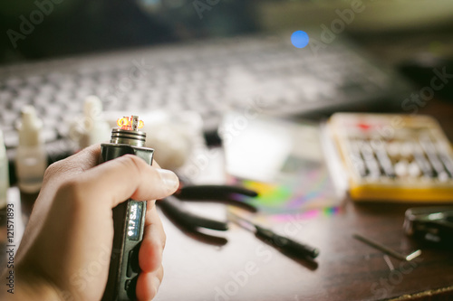 man prepares coil electronic cigarette smoking tasty vape juice. Device for the vaporization service. close up. heated coil