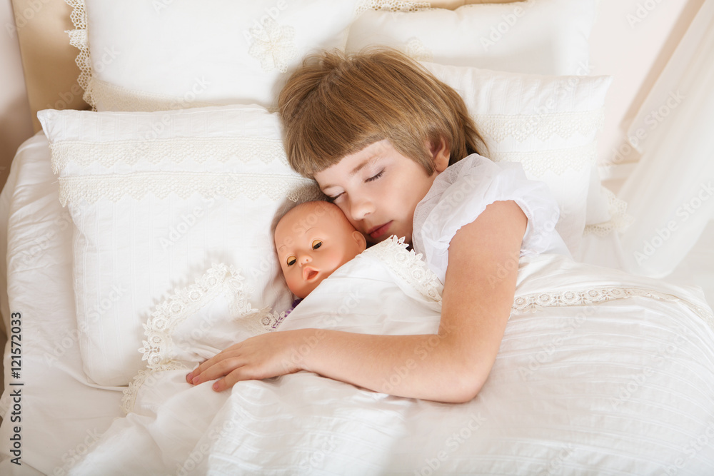 Adorable little child girl sleeping in the bed with her toy.

