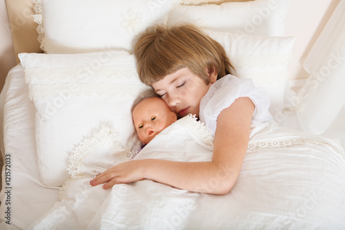 Adorable little child girl sleeping in the bed with her toy.