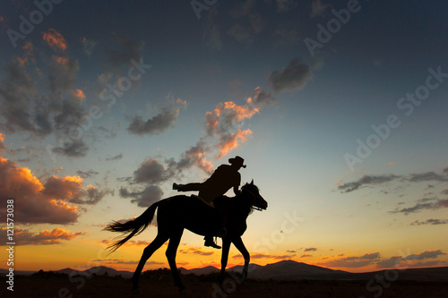 Silhouette of man riding a horse on sunset with beautiful backgr