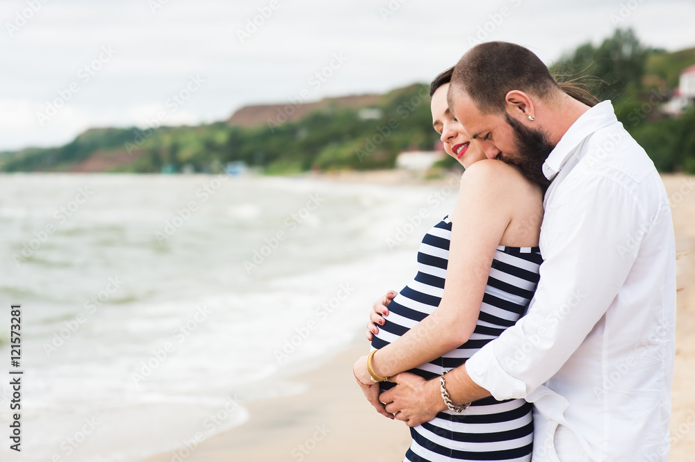 Beautiful young pregnant woman with man on the beach feel peace and tranquility