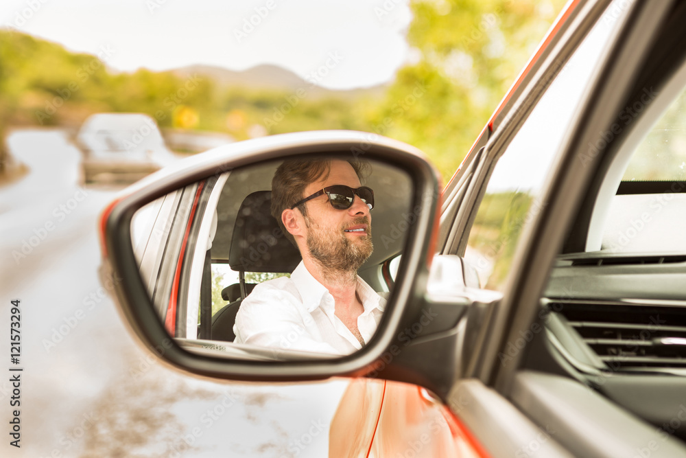 Naklejka premium Man (driver) reflected in a car wing mirror