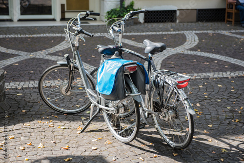 two bycicles standing on the street in the sun