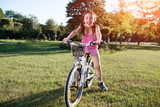 girl riding bicycle in summer sunset in the park