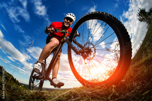 cyclist riding mountain bike on rocky trail at sunrise
