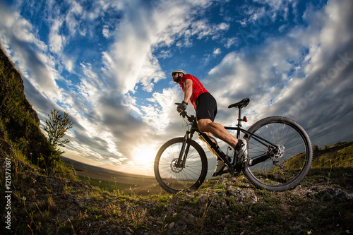 Fototapeta Naklejka Na Ścianę i Meble -  cyclist standing with mountain bike on trail at sunset