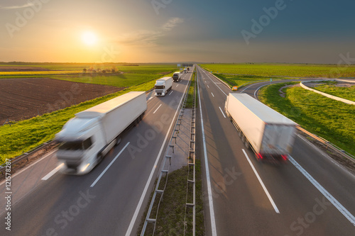 Modern white trucks on highway at idyllic sunset © rasica