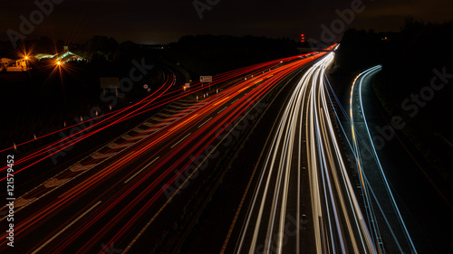 Road traffic at night with red, white and blue light trails