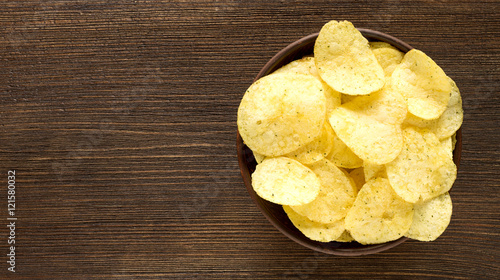 Potato chips in bowl on a table, top view.