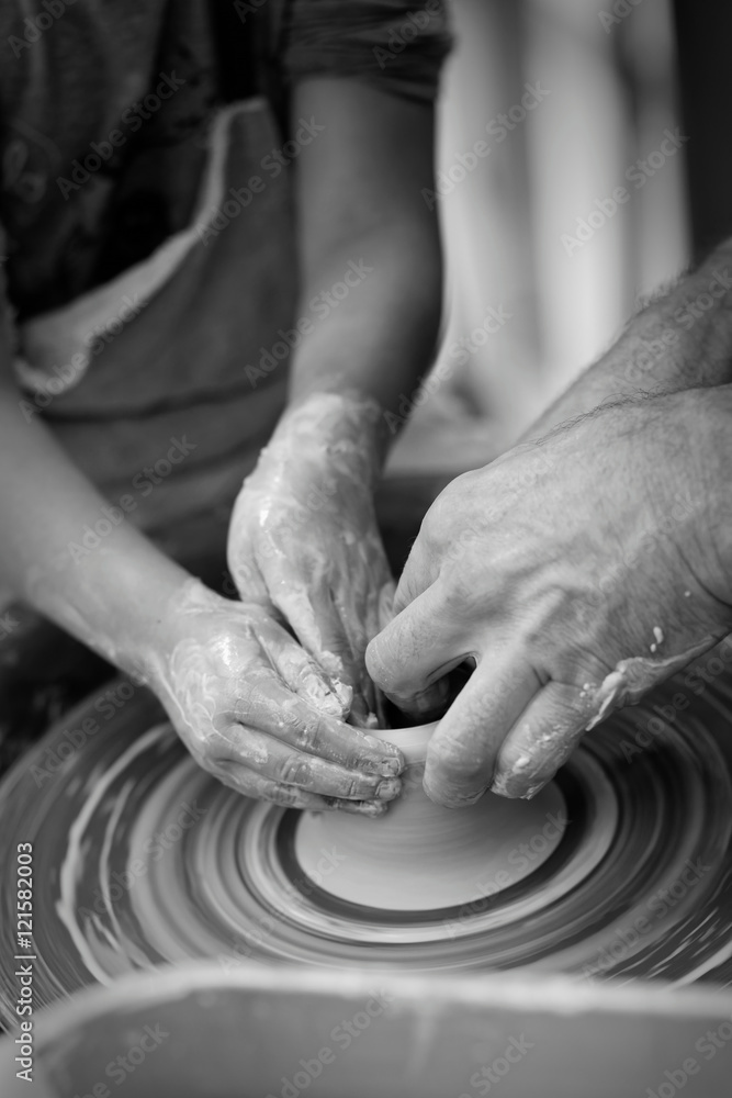 Hands of the potter and his young apprentice. Shallow focus.