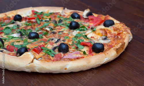 Pizza with mashrooms and chiken and olives on a wooden board