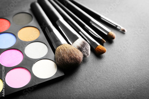 Make up brushes and eye shadow palette on black background