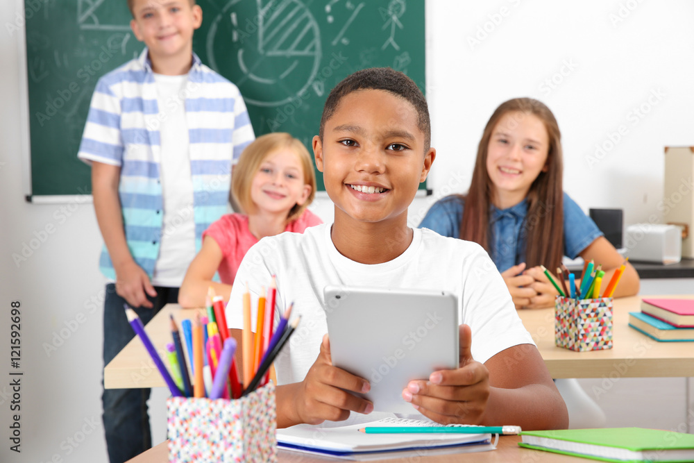 Fototapeta premium Pupil with tablet computer sitting in classroom