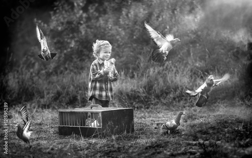 Little pigeon fancier. Boy playing with flying pigeons.