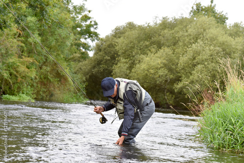 Fly-fisherman catching trout in irish river