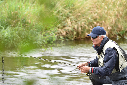 Fly fisherman fishing in river to catch brown trout
