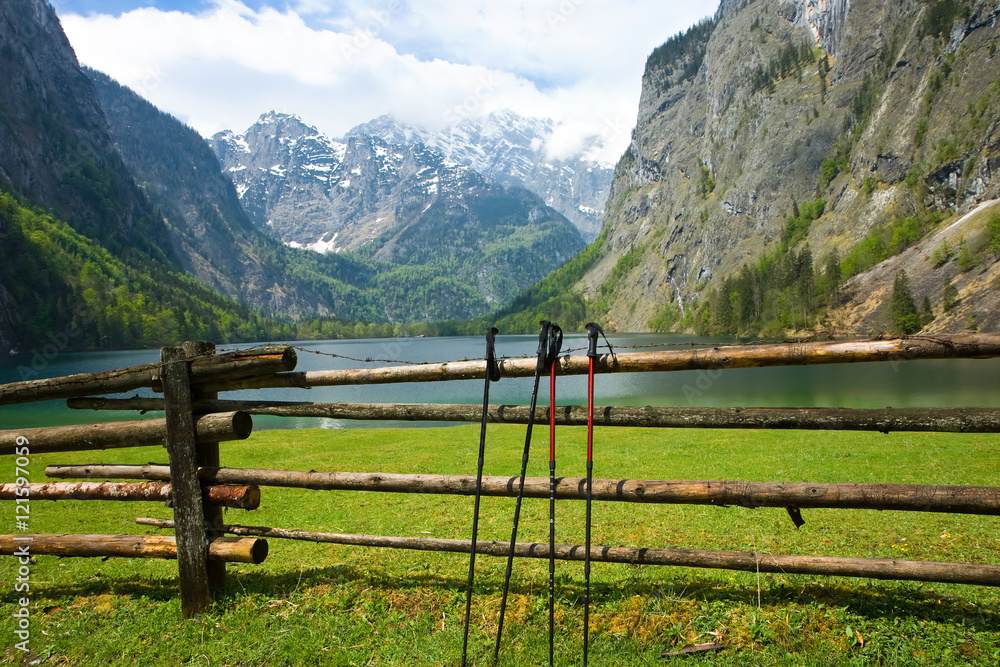 Nordic walking sticks on the fence with  Obersee and Watzmann peak in the background, Berchtesgaden Alps, Germany