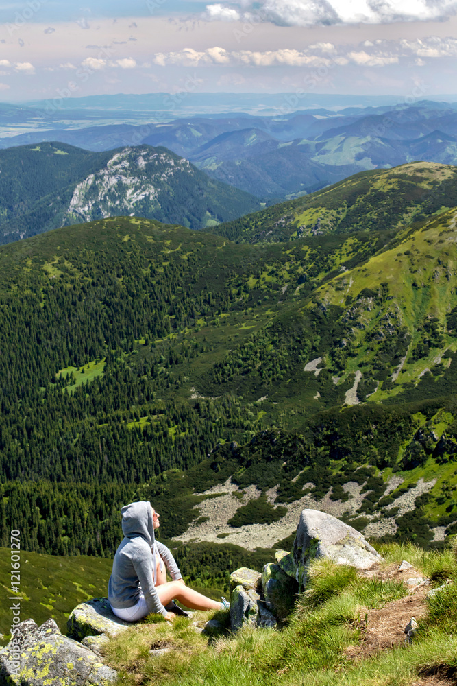 Freedom girl sitting on mountain top. Jasna, Demianovska Dolina, Low Tatras, Slovakia. Vertical photo.