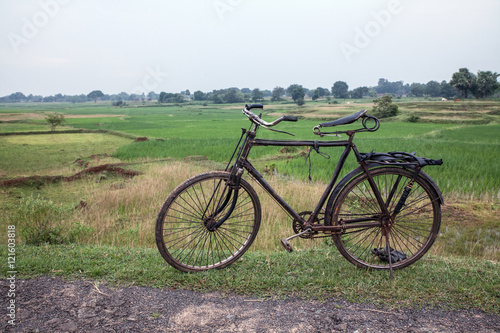 Old bike in front of rice paddies in an indigenous village in Jharkand, India photo