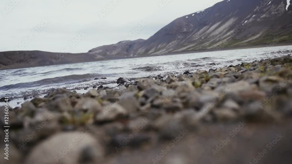 Sea waves on stones beach and mountains in Iceland Sea waves on stones beach and mountains in Iceland
