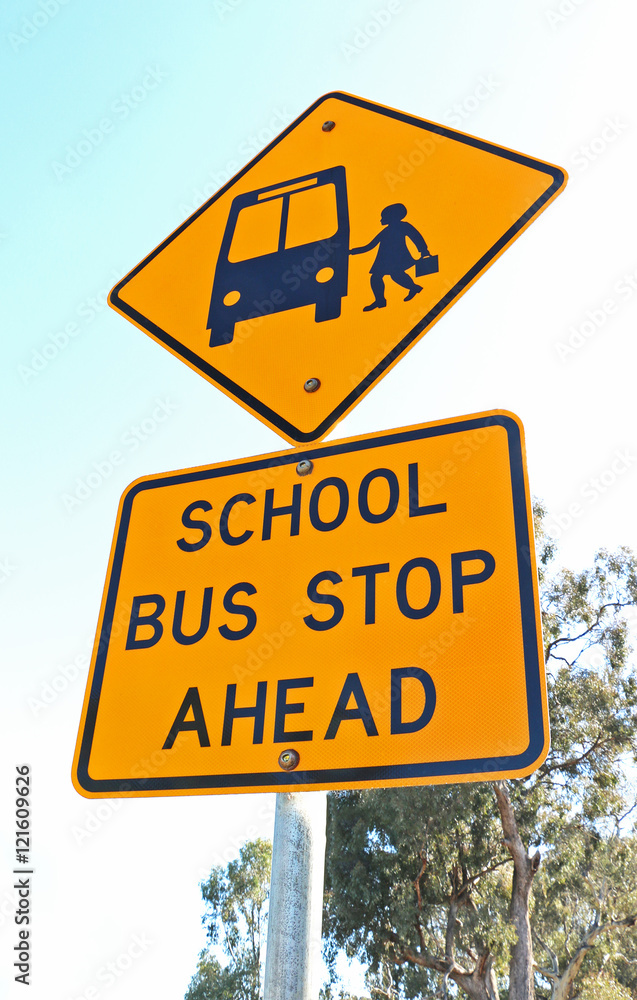 yellow and black school bus stop ahead sign and blue sky
