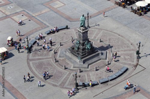 Adam Mickiewicz monument at the Main Market square with walking people. Aerial view from St. Mary Cathedral tower.