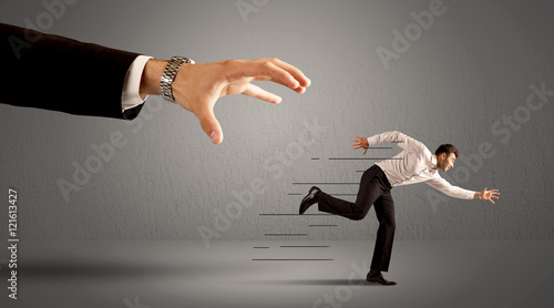 Businessman running away from a huge hand