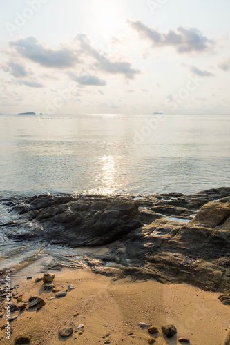 Rock on the beach with calm sea during sunrise in dawn