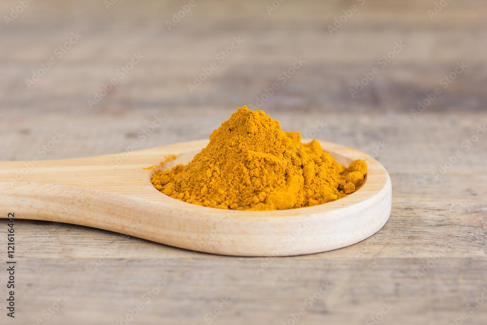 Turmeric powder in wood spoon on white background Turmeric powder in wood spoon on white background