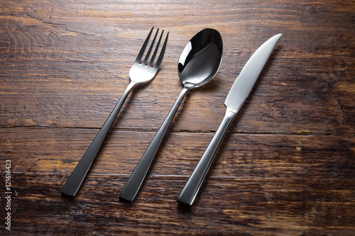 stainless fork spoon knife on the wooden table top