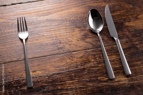 stainless fork spoon knife on the wooden table top