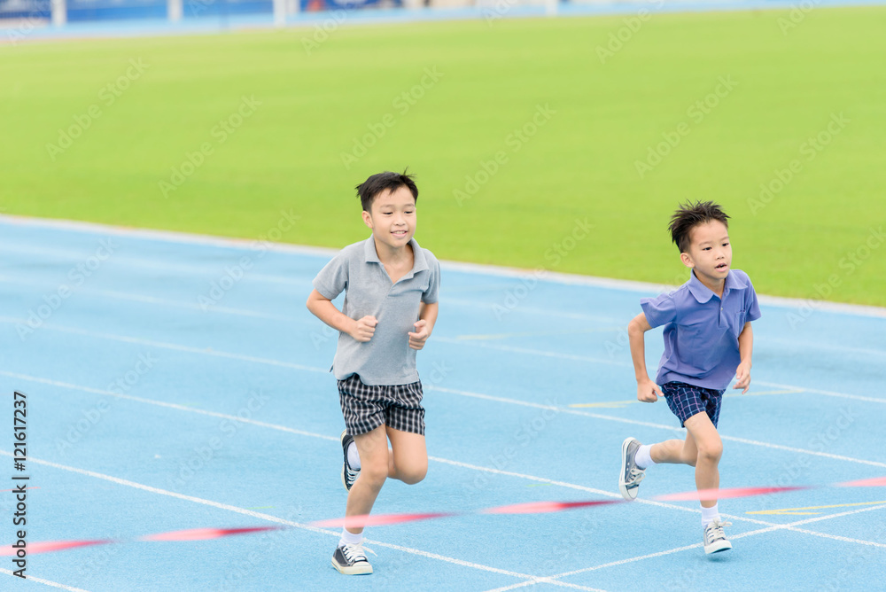 Fototapeta premium Young Asian boy running on blue track in the stadium