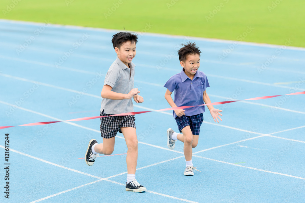 Young Asian boy running on blue track in the stadium