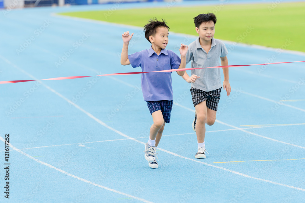 Fototapeta premium Young Asian boy running on blue track in the stadium