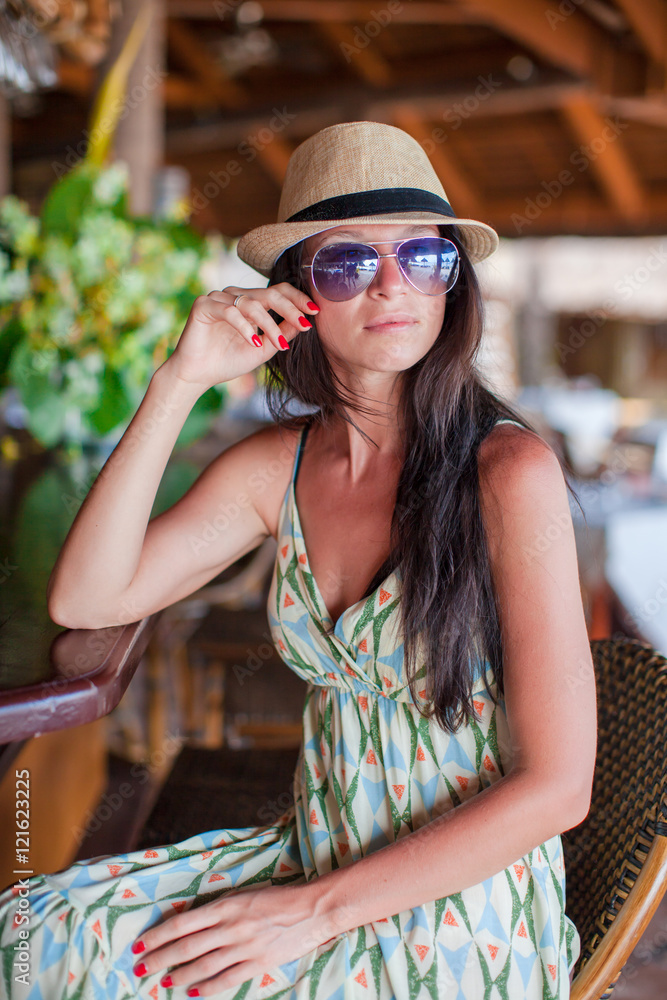 Beautiful brunette woman in long dress and hat relaxing in beach restaraunt Beautiful brunette woman in long dress and hat relaxing in beach restaraunt