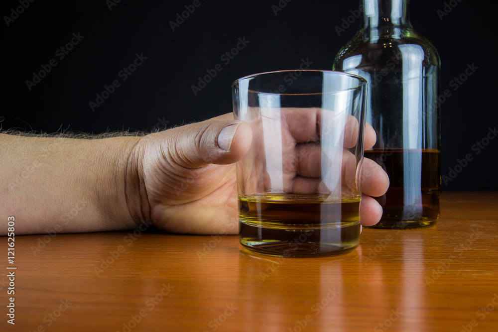 eine Hand greift nach einem Glas mit Alkohol eine Hand greift nach einem Glas mit Alkohol