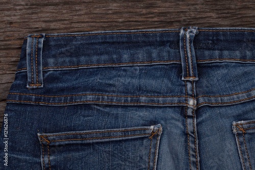 Blue jeans on a brown wooden background.