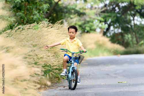 Fototapeta Naklejka Na Ścianę i Meble -  Boy riding bicycle on the road.