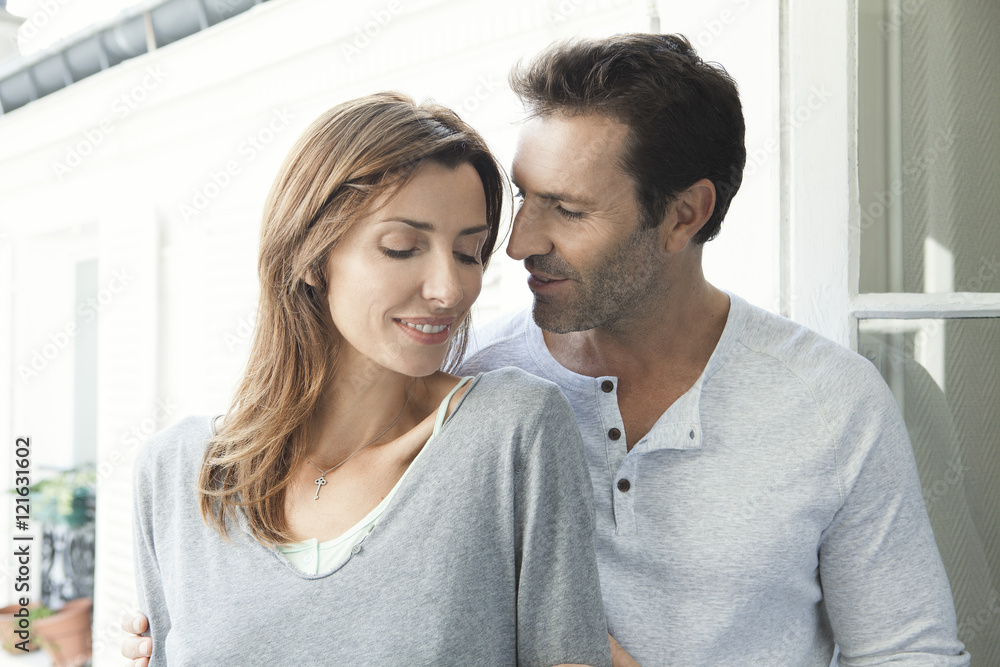 Smiling couple standing together near open window Smiling couple standing together near open window