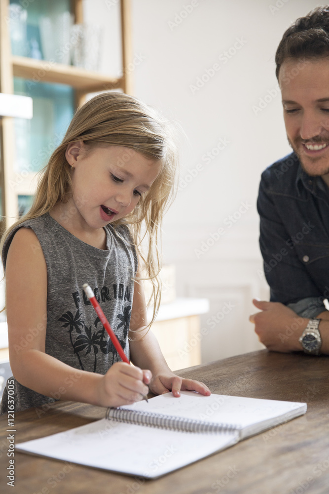 Father watching young daugther practice writing Father watching young daugther practice writing