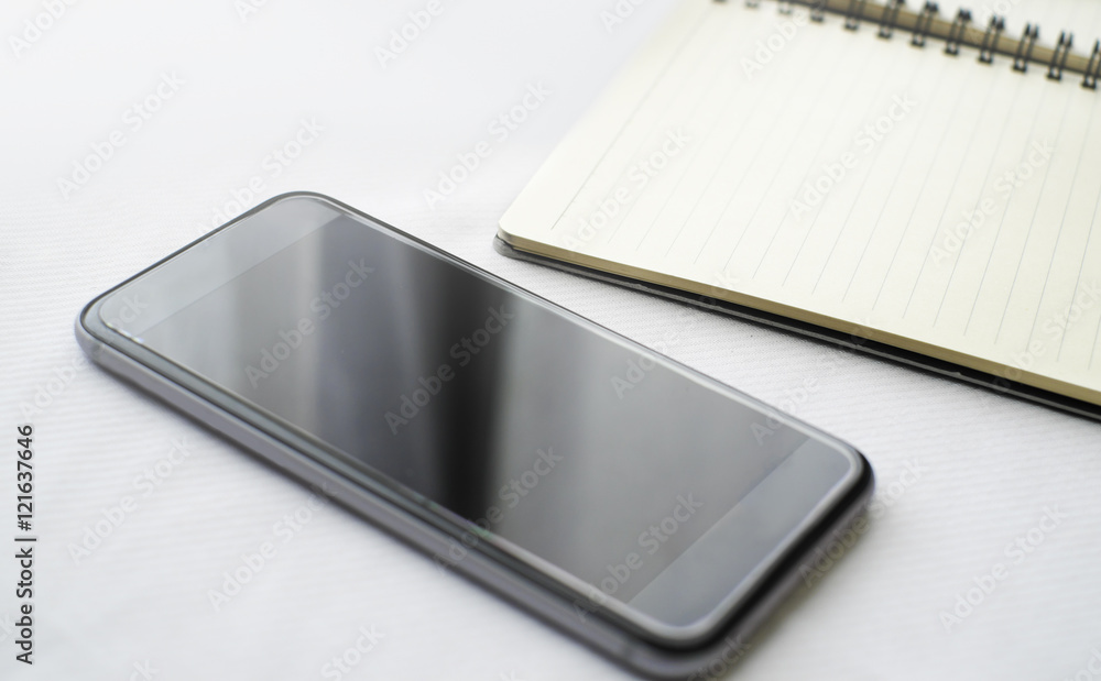 Smartphone on blank notebook with space on white background Smartphone on blank notebook with space on white background