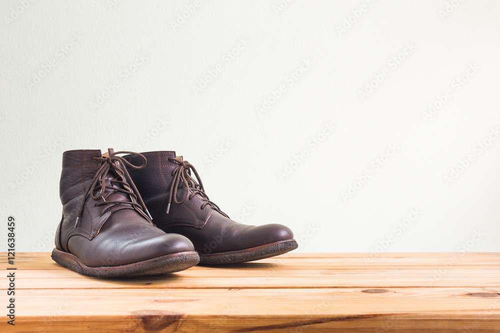 Men's fashion with brown boots on wooden table over wall background