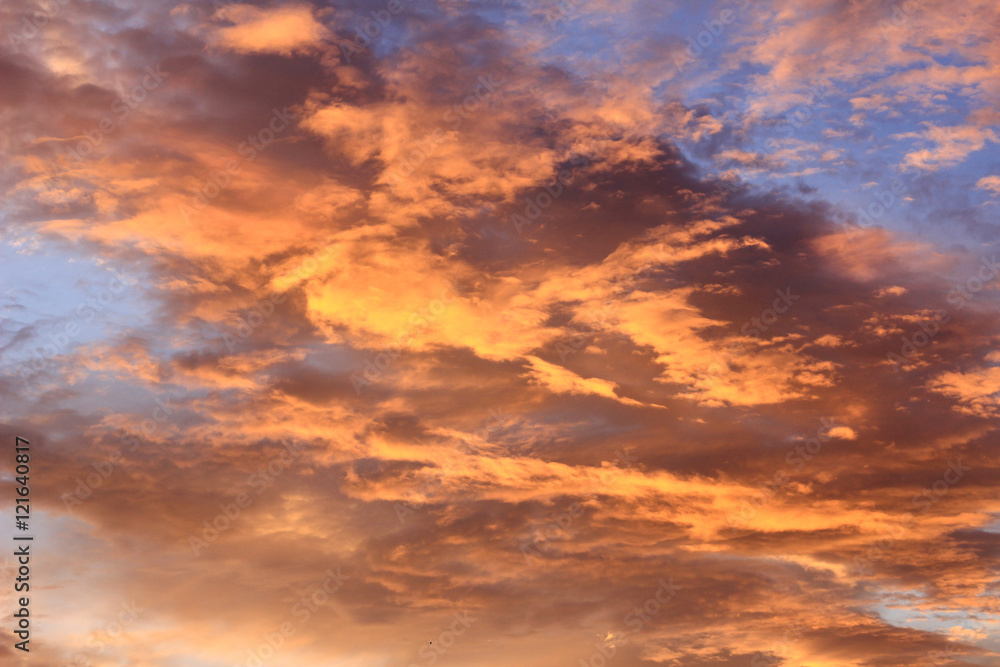 Fiery sunset with orange cloud and blue sky