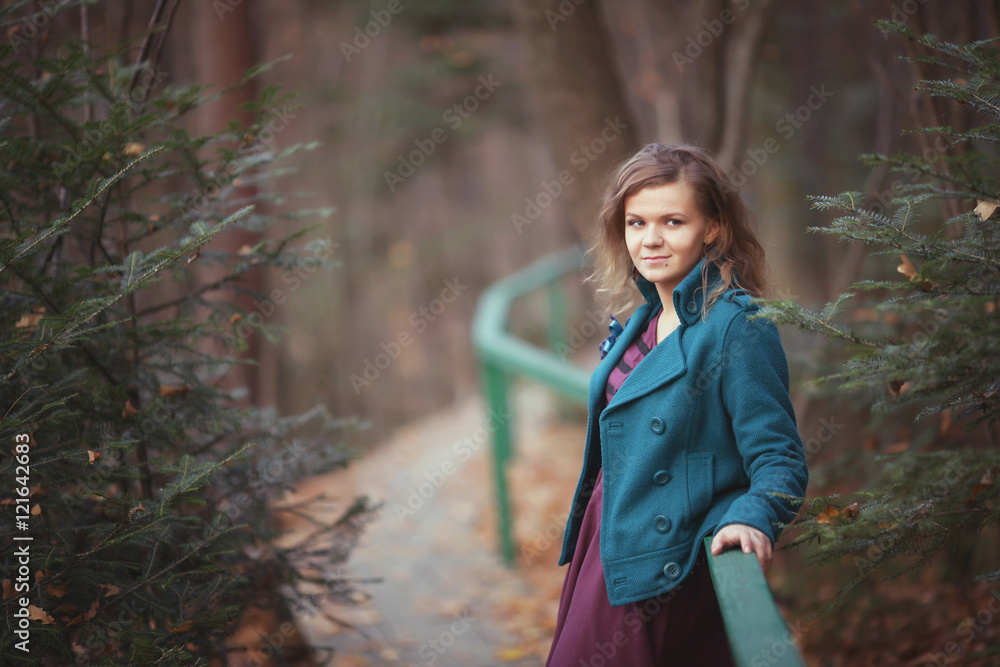 Happy fall woman sitting on countryside fence smiling joyful in autumn forest. Young beautiful multicultural Caucasian woman model outdoors Happy fall woman sitting on countryside fence smiling joyful in autumn forest. Young beautiful multicultural Caucasian woman model outdoors