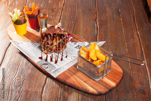 pork steak with French fries on a wooden cutting board photo