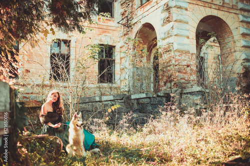 Young beautiful woman in a long dress and her dog (husky) walking in autumn in a city park. Farytale. Long hair girl in long green dress and coat. © nataliakabliuk