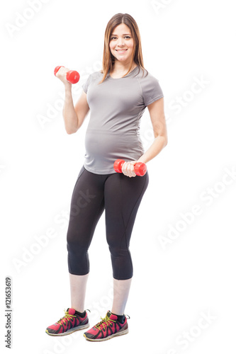 Cute pregnant woman lifting weights
